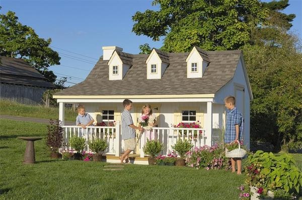 Amish kids cottage playhouse with dormers, covered porch, and flower boxes.