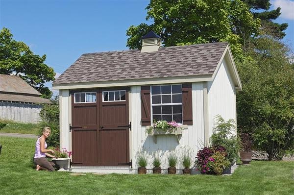 Amish Pinehurst shed with shutters, flower boxes, and transom windows above the doors.