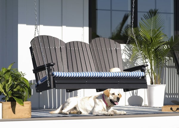 Hanging porch swing with dog in front of it.